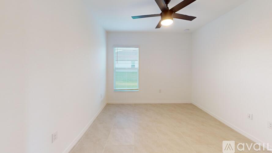 A room with a ceiling fan and a window with blinds.