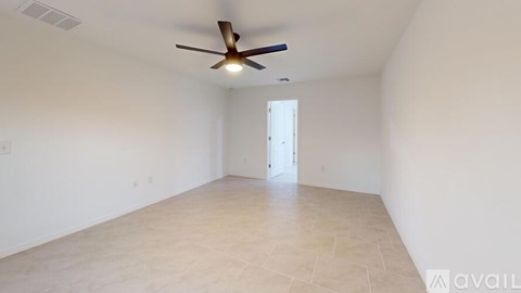 A spacious room with a ceiling fan and a door in the background.