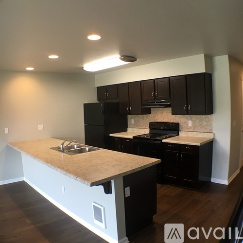 A kitchen with black cabinets and a beige island.