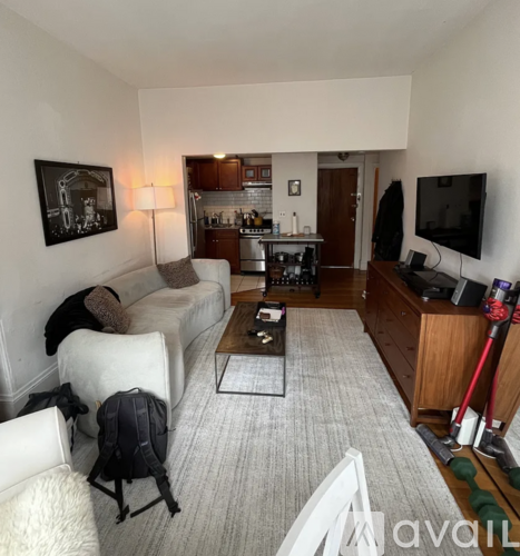 A living room with a couch, a chair, a coffee table, and a television.
