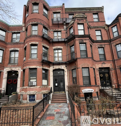 A red brick building with a black iron fence in front.