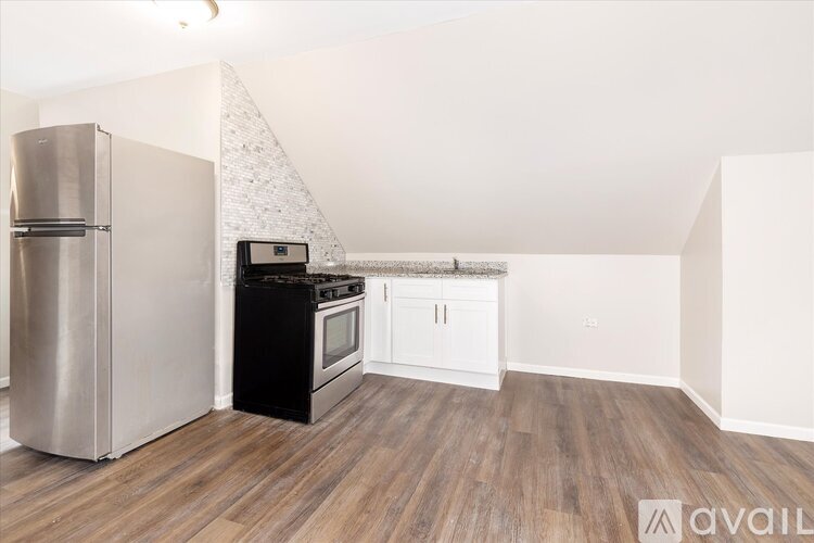 A kitchen with a stainless steel refrigerator and a black stove top oven.