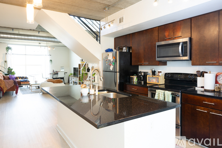 A kitchen with a black refrigerator and stove top oven.