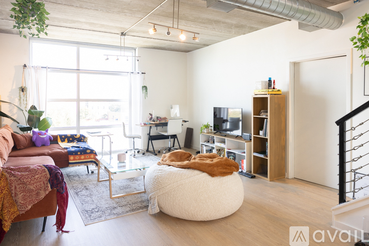 A living room with a couch, a chair, a table, a bean bag, a bookshelf, and a staircase.