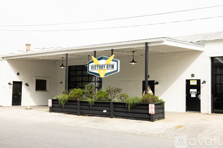 A white building with a black door and a sign that says "Victory Gym".