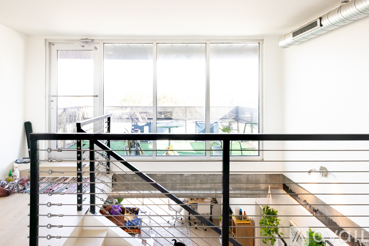 A balcony with a black railing and a view of a pool and trees.