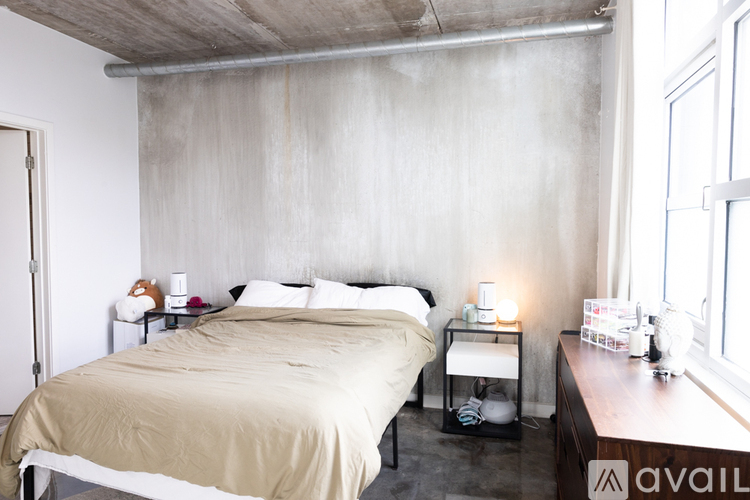 A bedroom with a large bed and a concrete wall.