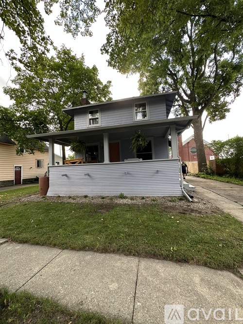 A house with a grey roof and a brown door is surrounded by trees.