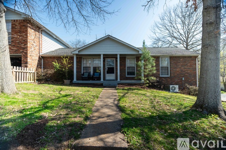 A house with a front yard and a tree in front of it.