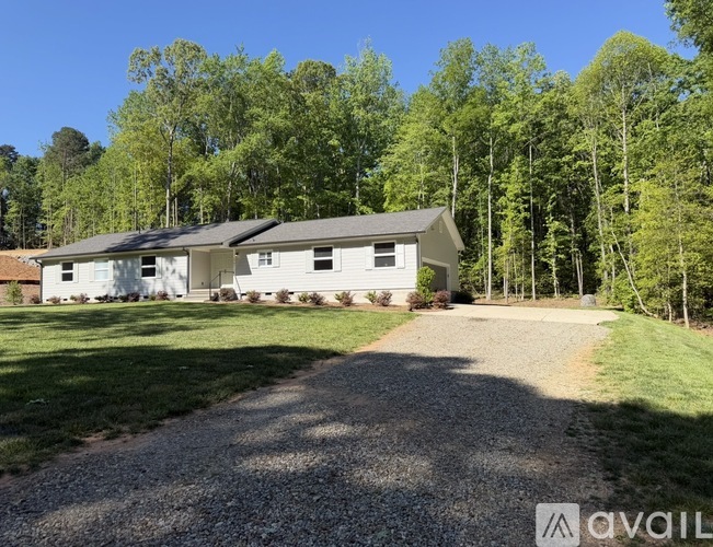 A house with a gravel driveway in front of it is for sale.