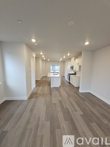 A spacious room with wooden flooring and white walls.