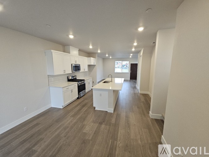 A spacious kitchen with white cabinets and a wooden floor.