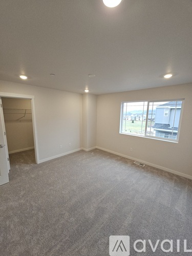 A room with a carpeted floor and a window showing a building outside.