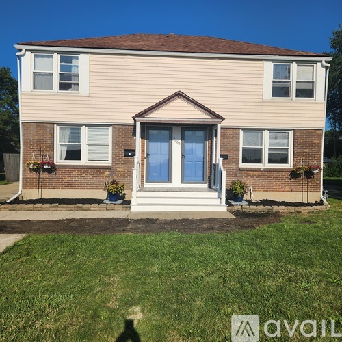 A house with a front yard and a blue sky in the background.
