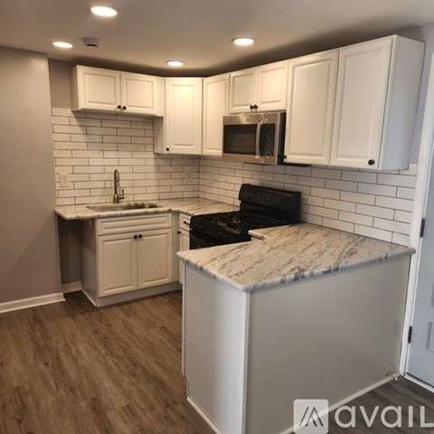 A kitchen with white cabinets and a marble countertop.