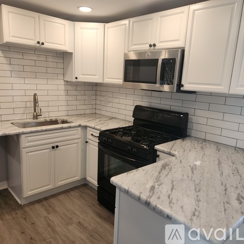 A kitchen with white cabinets and a black stove top oven.