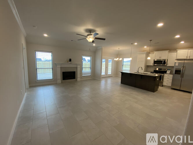 A spacious kitchen and living room with a ceiling fan and tiled flooring.