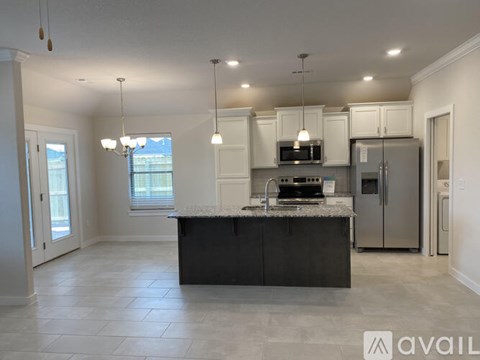 A kitchen with a large island in the middle and a refrigerator to the right.