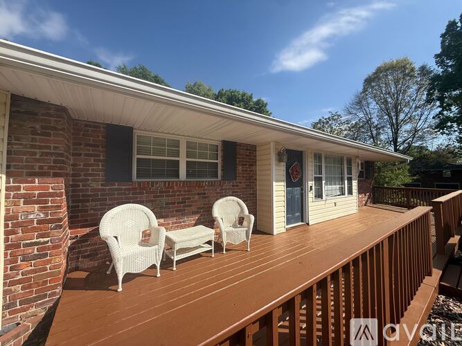 A house with a wooden deck and white chairs.