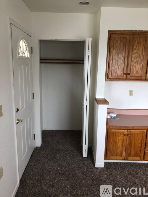 A small kitchen with a refrigerator, cabinets, and a doorway leading to another room.