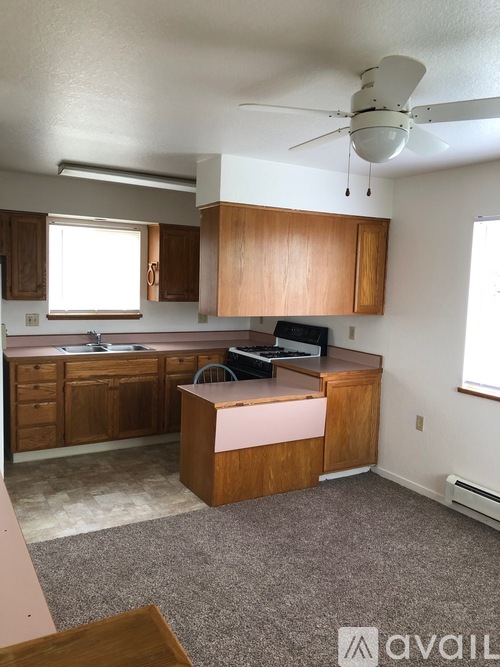 A kitchen with wooden cabinets and a white ceiling fan.