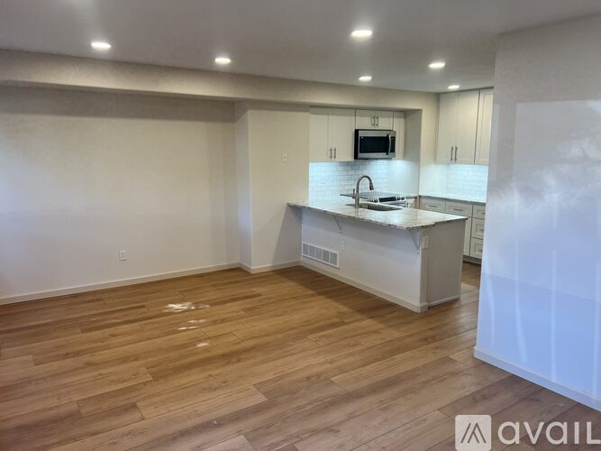 A kitchen with a wooden floor and white cabinets.