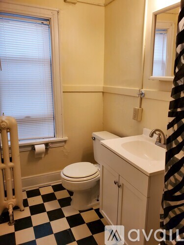 A bathroom with a toilet, sink, and checkered floor.