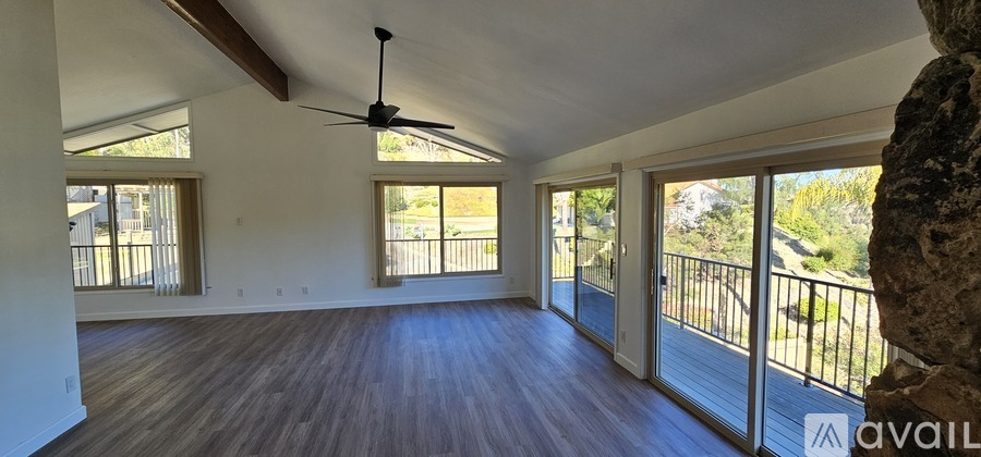 A spacious room with wooden floors and a balcony with a railing.