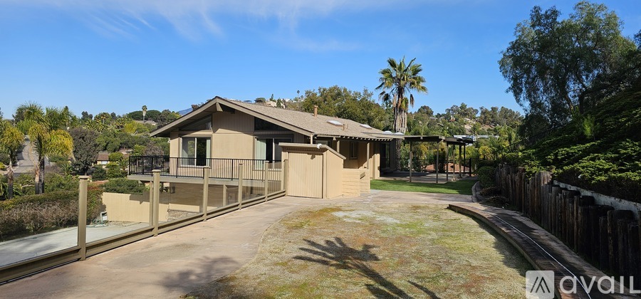 A house with a fence and trees in the background.