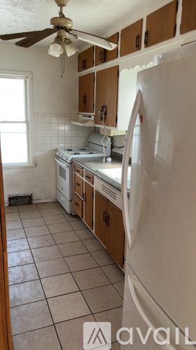 A kitchen with a white refrigerator, wooden cabinets, and a ceiling fan.