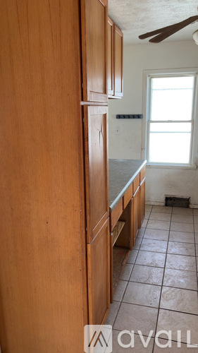A kitchen with wooden cabinets and a tiled floor.
