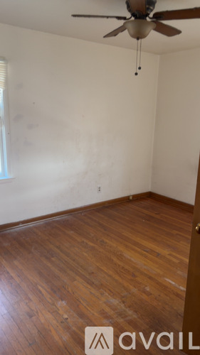 A room with a ceiling fan and wooden floors.