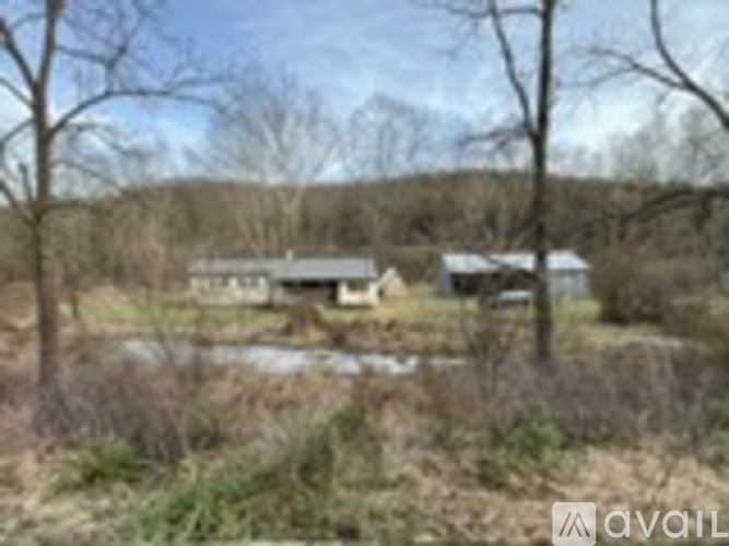 A rural landscape with a house and a pond.