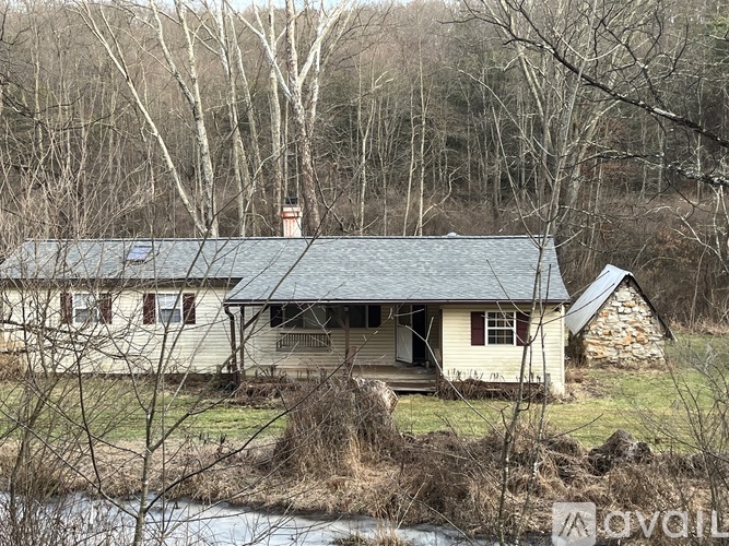 A house with a grey roof is surrounded by trees and grass.
