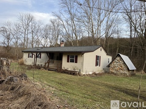 An old house with a broken window is surrounded by trees.