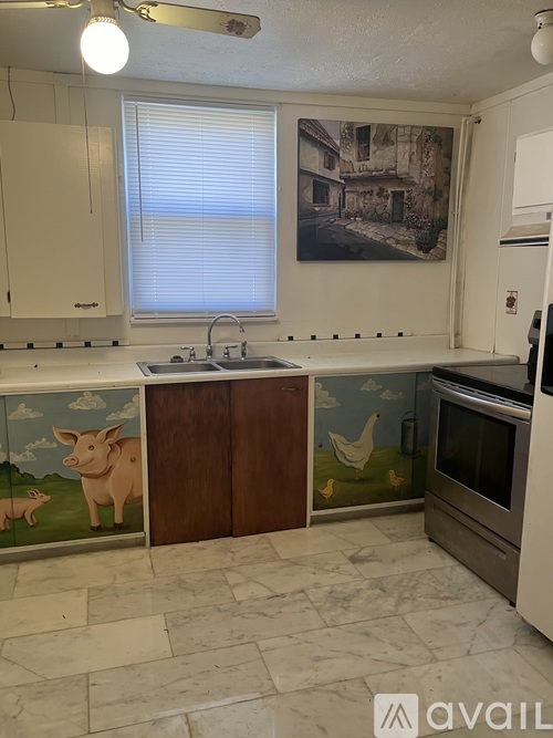 A kitchen with a painting of a house on the wall.