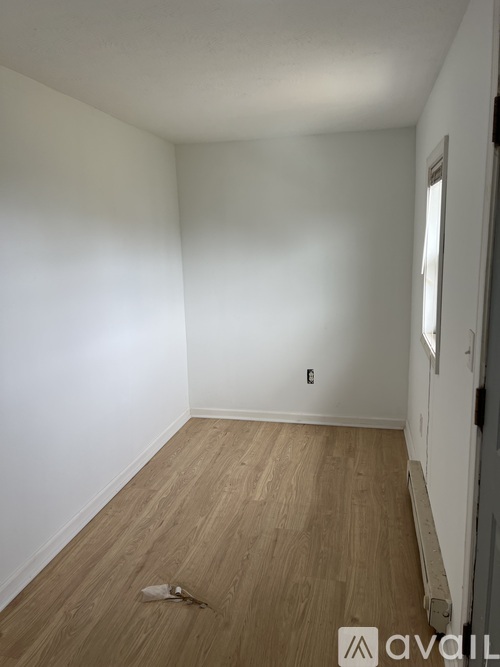 A room with wooden flooring and white walls.