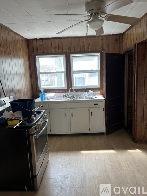 A kitchen with wooden walls and a fan on the ceiling.