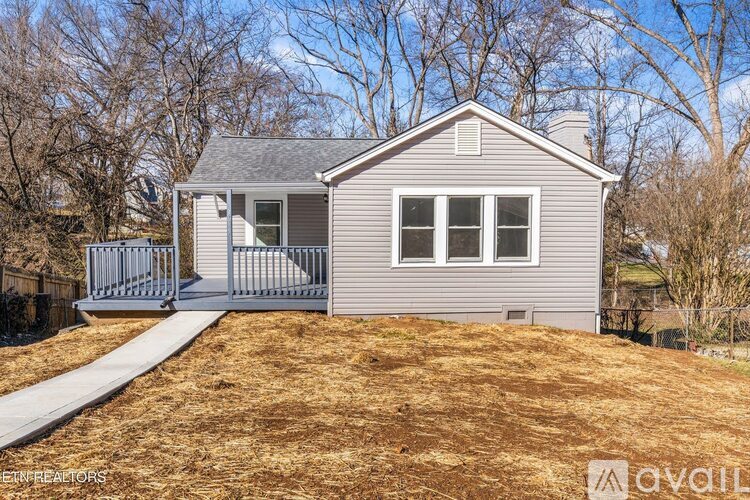 A house with a grey siding and a white roof is for sale.