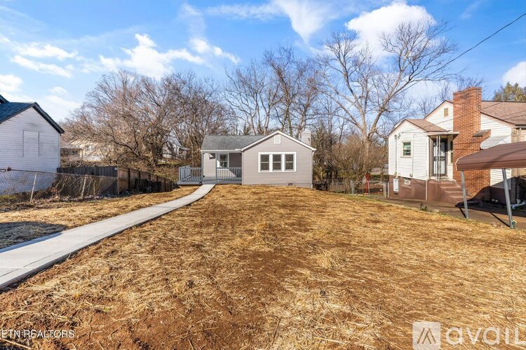 A house with a brown roof is surrounded by a fence and a grassy area.