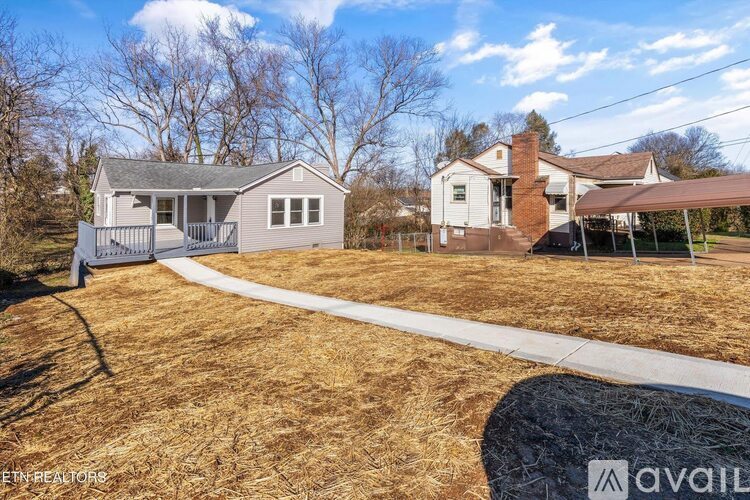 A house with a grey roof and a white fence is for sale.