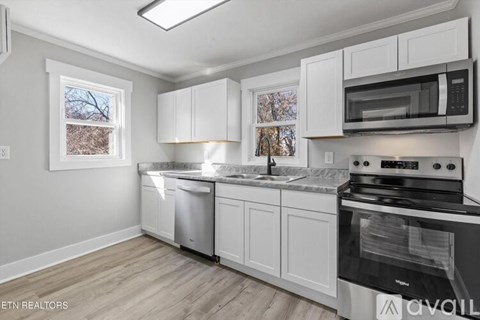 A kitchen with white cabinets and a black stove top oven.