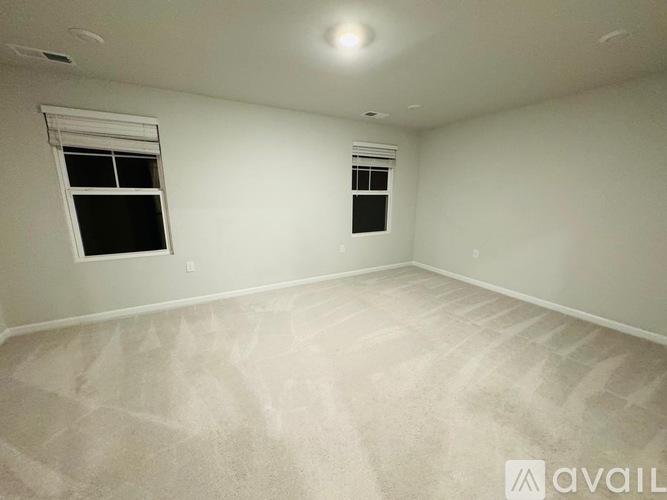 A room with two windows and carpeted flooring is available for rent or purchase.