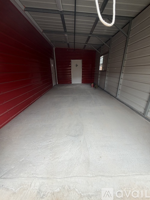 A large empty room with a red wall and a white door.
