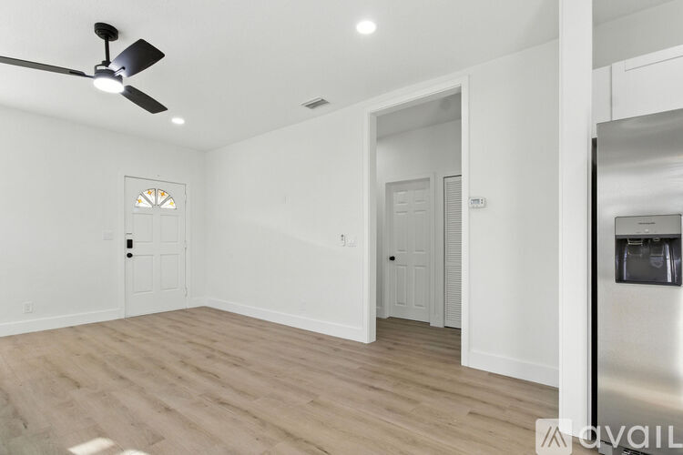 A spacious room with a ceiling fan and wooden flooring.