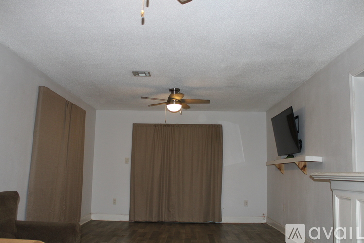 A living room with a ceiling fan and a television on a stand.