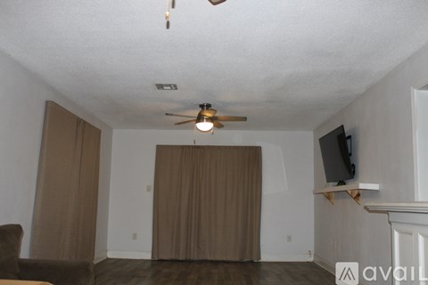 A living room with a ceiling fan and a television on a stand.