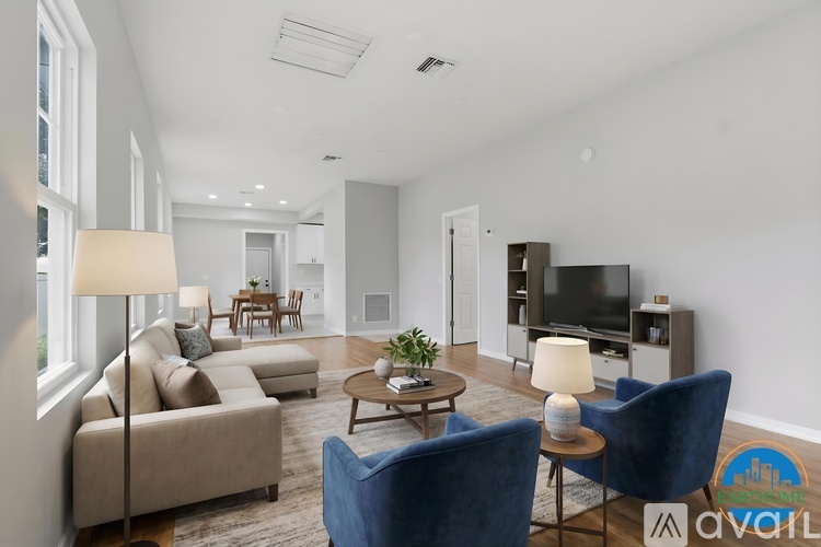 A living room with a beige couch, a blue chair, a coffee table, and a television.