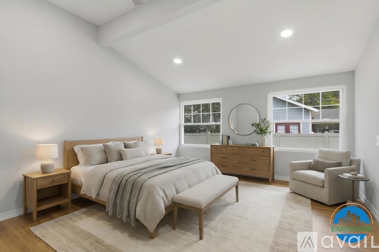 A bedroom with a large bed, a chair, and a nightstand with a lamp.