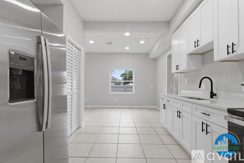 A modern kitchen with white cabinets and a stainless steel refrigerator.